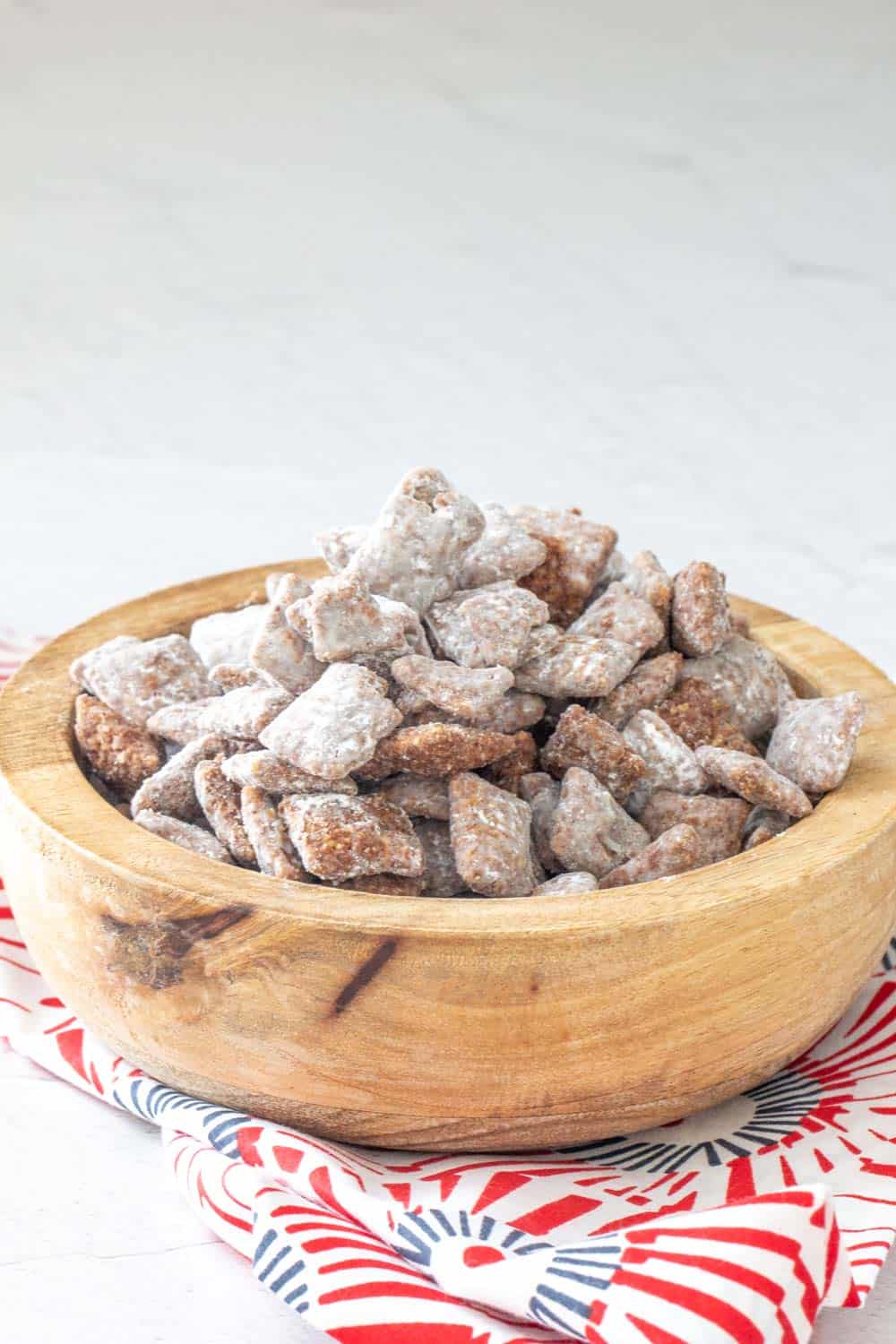 puppy chow snack mix in a brown bowl with a festive napkin underneath