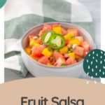 A vibrant bowl of fruit salsa featuring watermelon, mango, jalapeño, and red onion sits atop a checkered cloth. At the bottom, the words "Fruit Salsa" invite you to savor its refreshing zing.