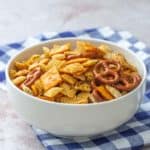 taco chex mix in a white bowl with blue checked napkin