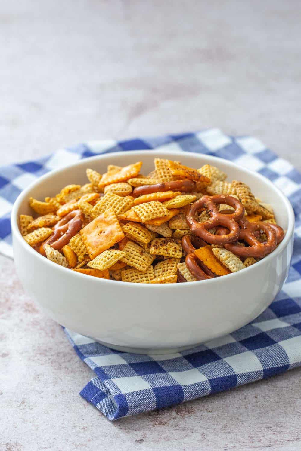 taco chex mix in a white bowl with blue checked napkin