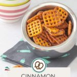 A bowl of cinnamon sugar pretzels rests on a dark napkin, flanked by vibrant stacked bowls. The label proudly displays "Cinnamon Sugar Pretzels" and the whimsical "happysnackcidents.com.