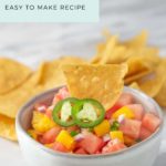 A bowl of refreshing fruit salsa featuring watermelon, mango, jalapeño slices, and red onion, crowned with a crunchy tortilla chip. Perfectly sweet and spicy! Text: "Fruit Salsa Easy to Make Recipe.