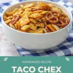 A white bowl brimming with taco Chex mix, pretzels, and snacks rests on a blue-checkered cloth. Text reads: "Homemade Recipe Taco Chex Mix HappySnackcidents.com.