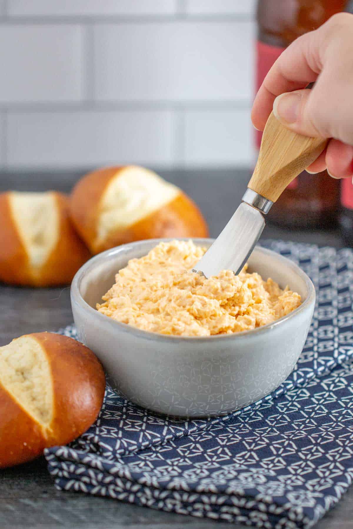 hand holding spreader in beer cheese dip