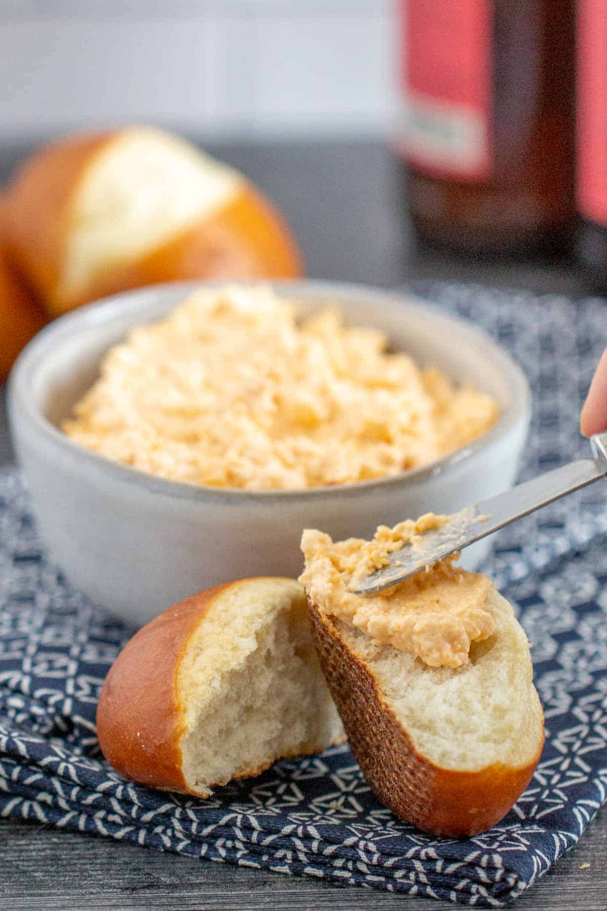 spreading beer cheese onto pretzel roll