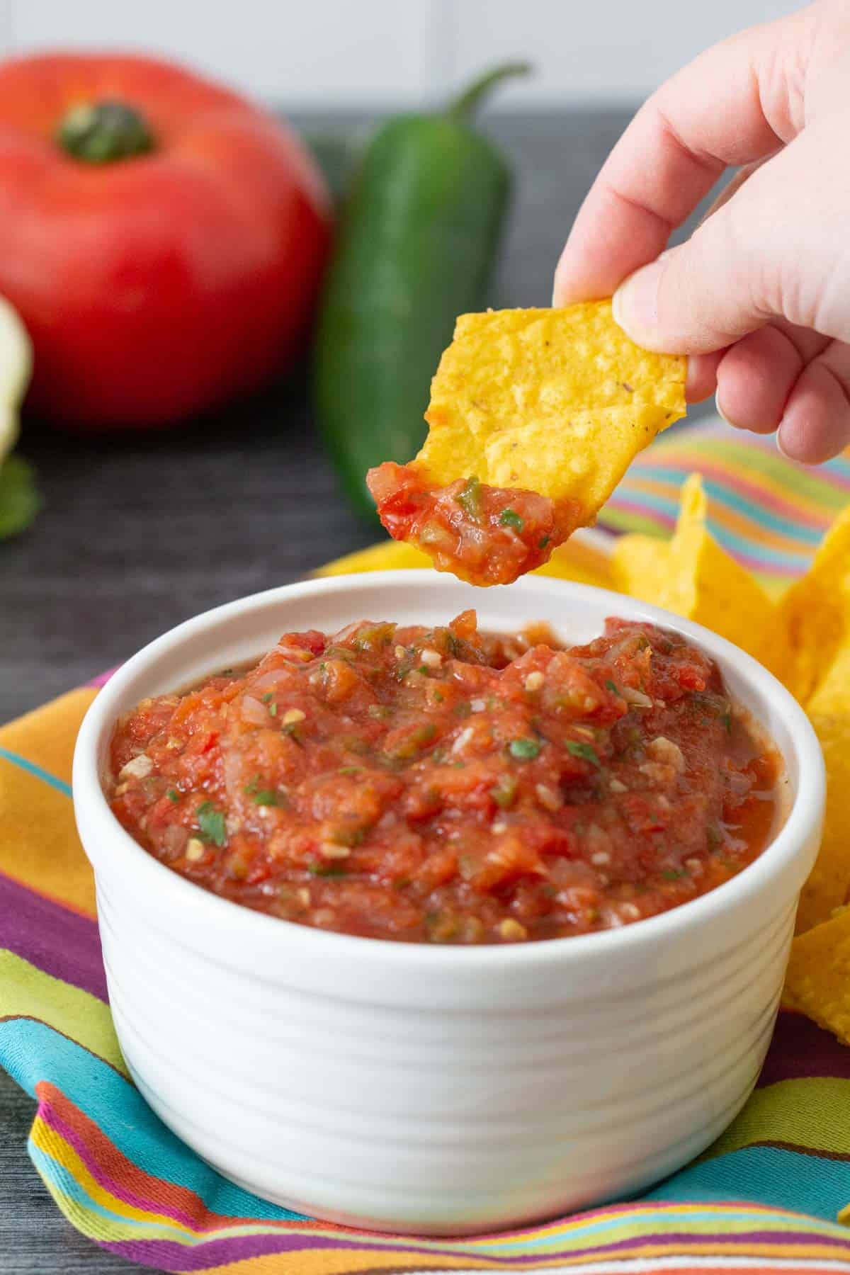 hand scooping salsa onto chip