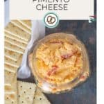 A jar of creamy pimento cheese sits invitingly beside crispy saltine crackers. Discover this easy-to-make recipe at "happysnackcidents.com," where delightful snacking adventures await!.