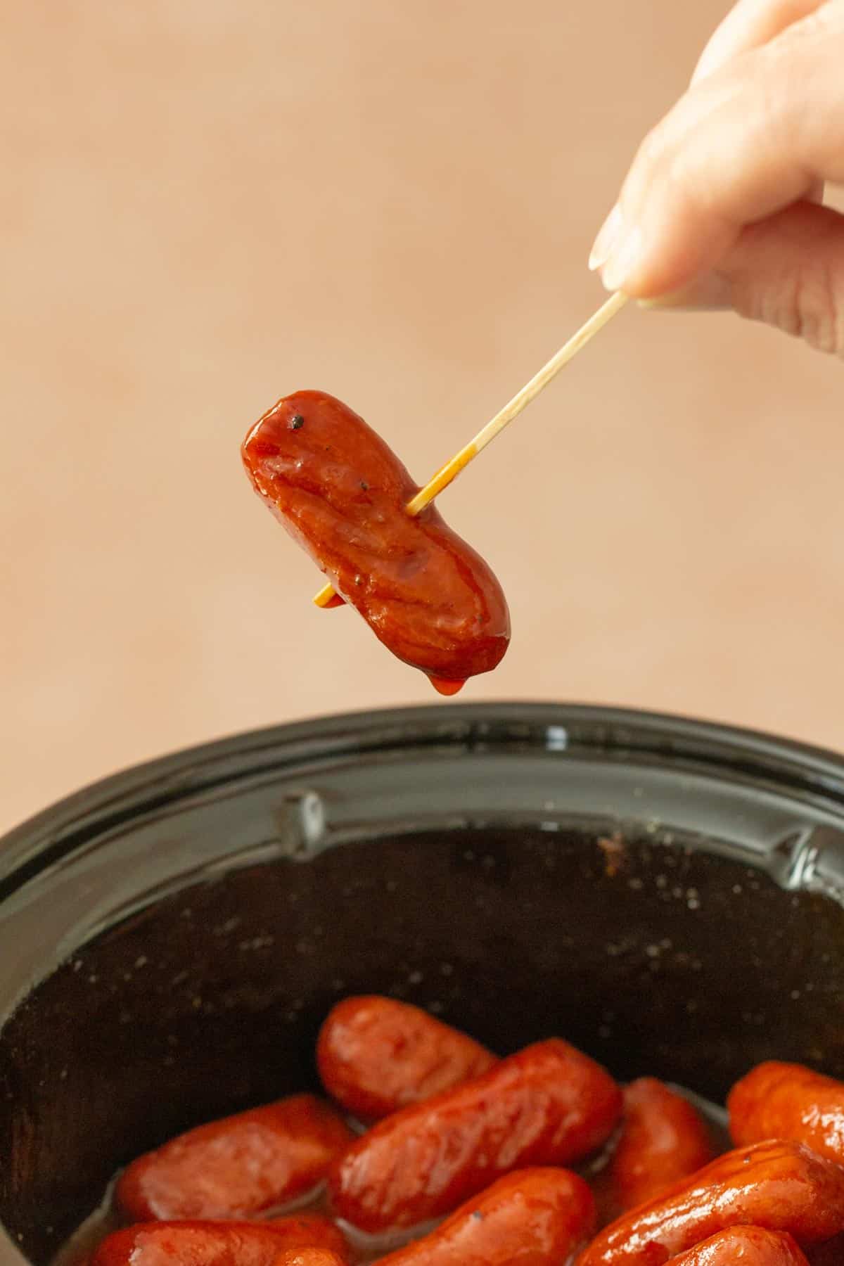 hand spearing cocktail sausage with toothpick