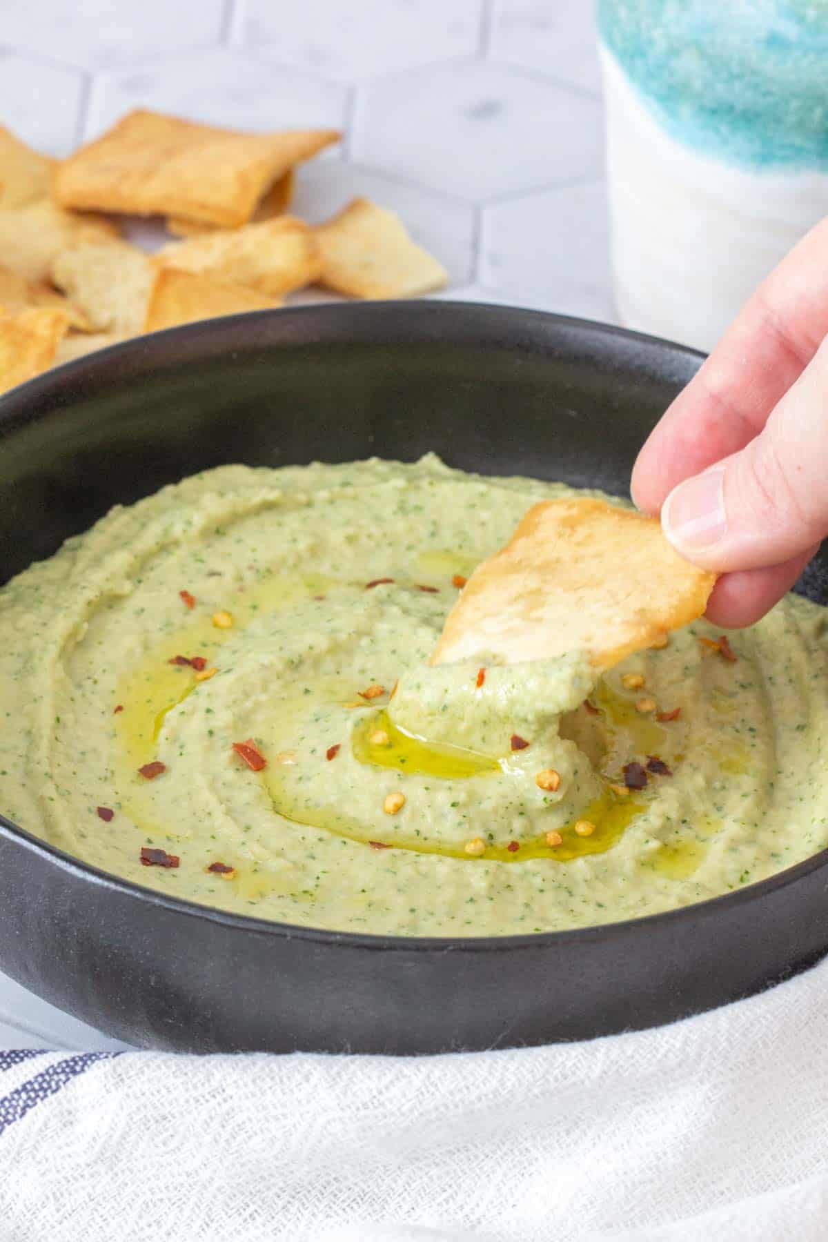 pita chip dipping into white bean dip