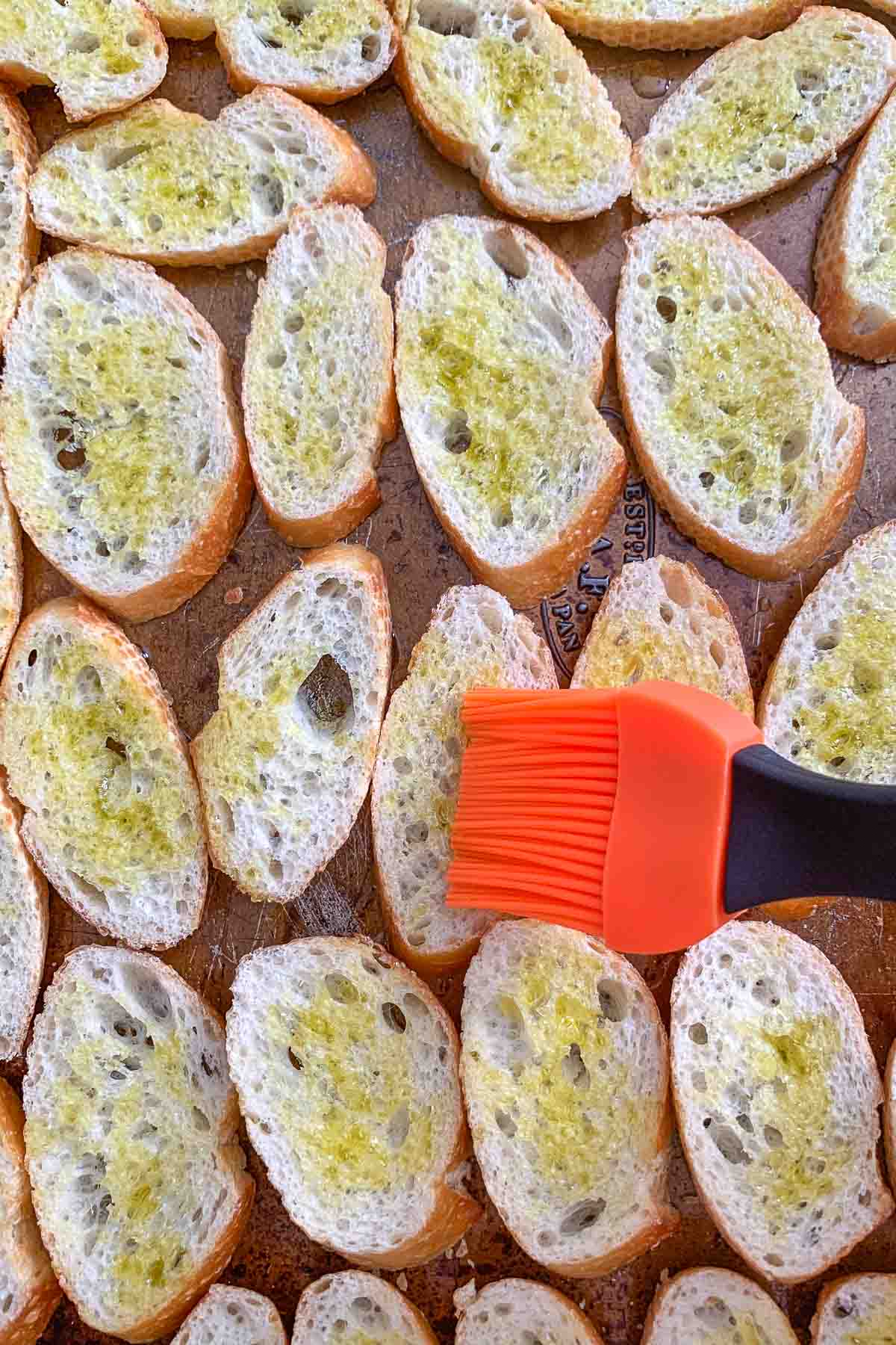 brushing olive oil onto bread for crostini