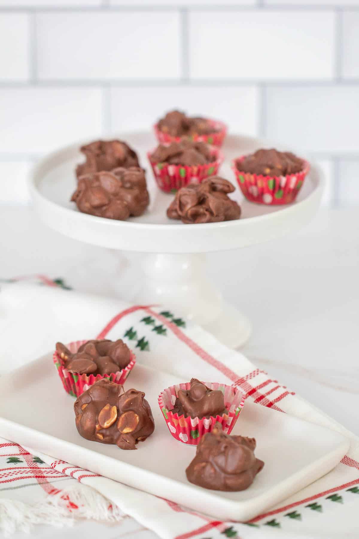 peanut clusters on a tray and cake stand with christmas towel