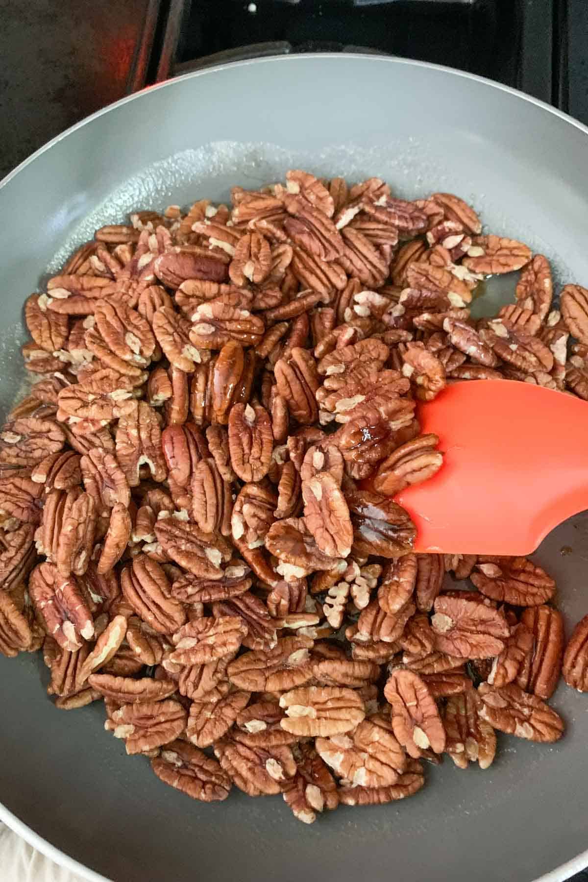 mixing pecans with melted butter and sugar in saute pan