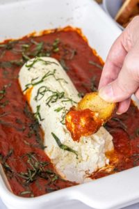 scooping baked goat cheese onto crostini