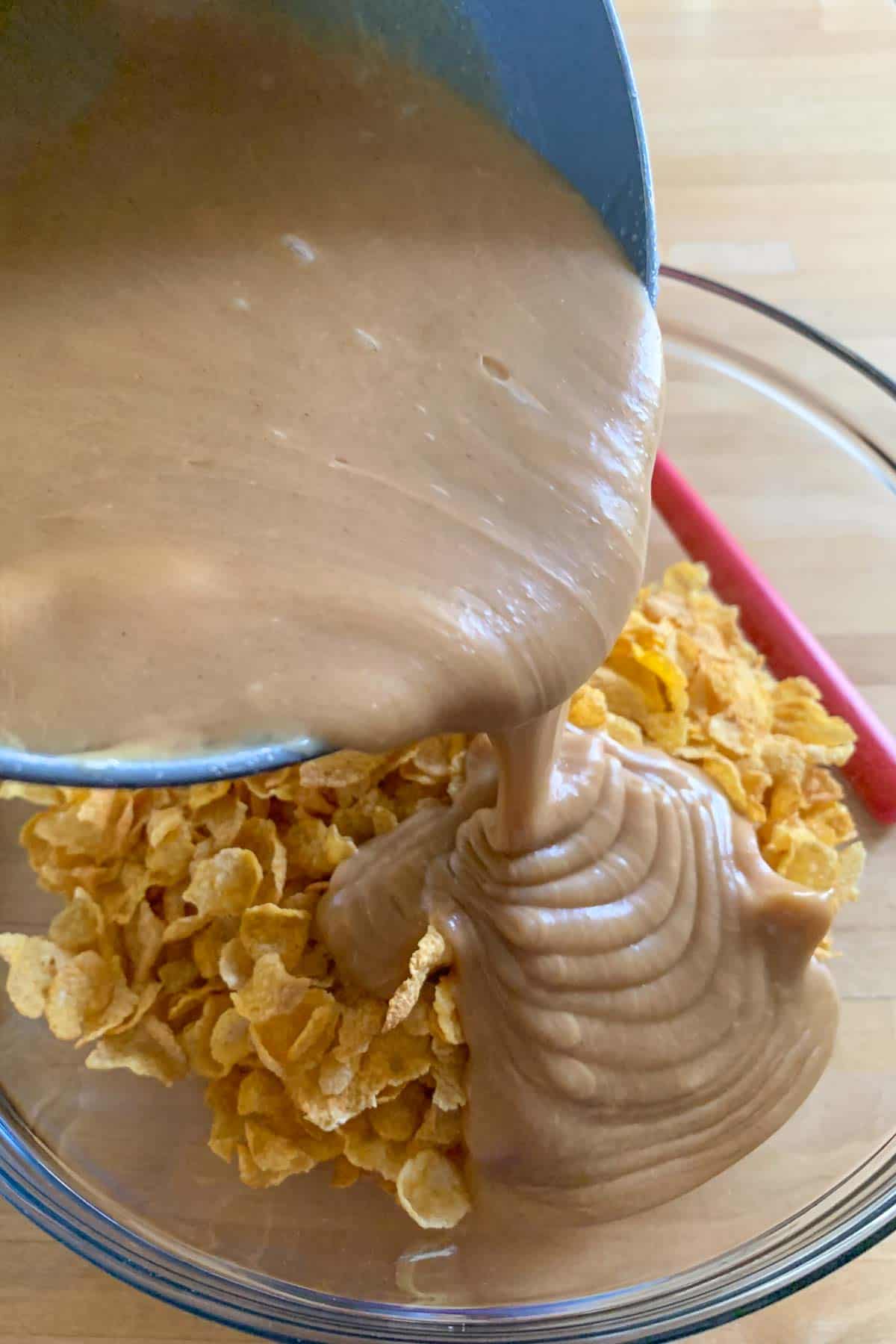 pouring peanut butter mixture into cornflakes to make cookies