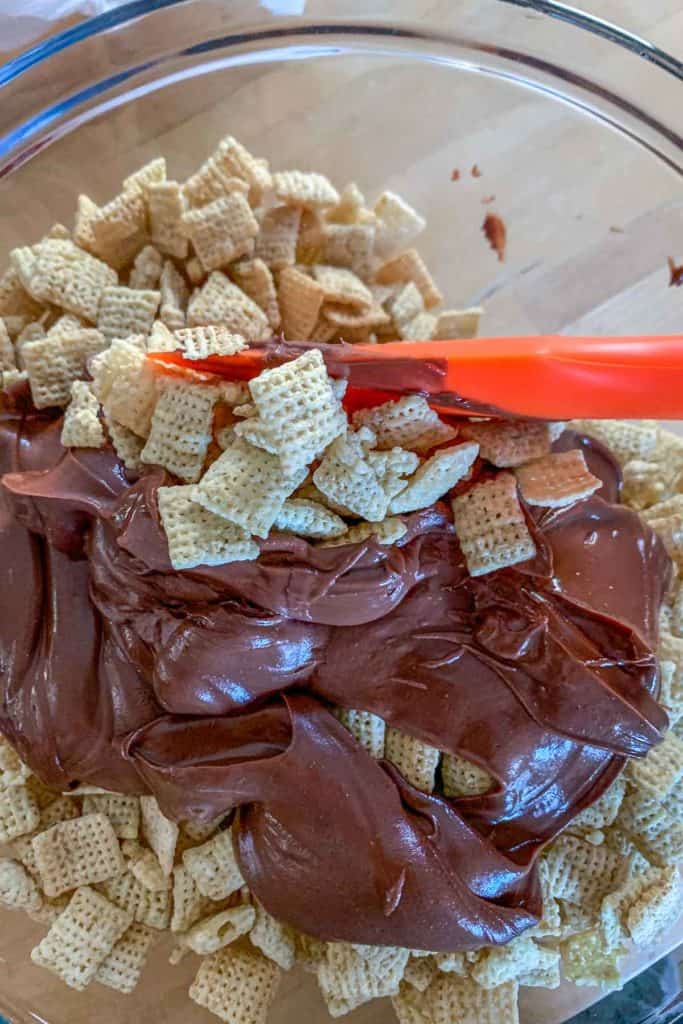 Mixing peanut butter and melted chocolate with chex cereal.