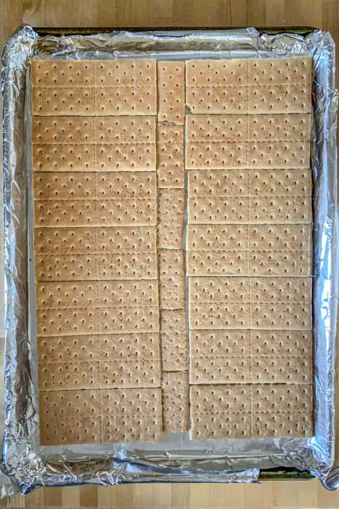 Graham crackers arranged in a single layer on a sheet pan lined with foil.