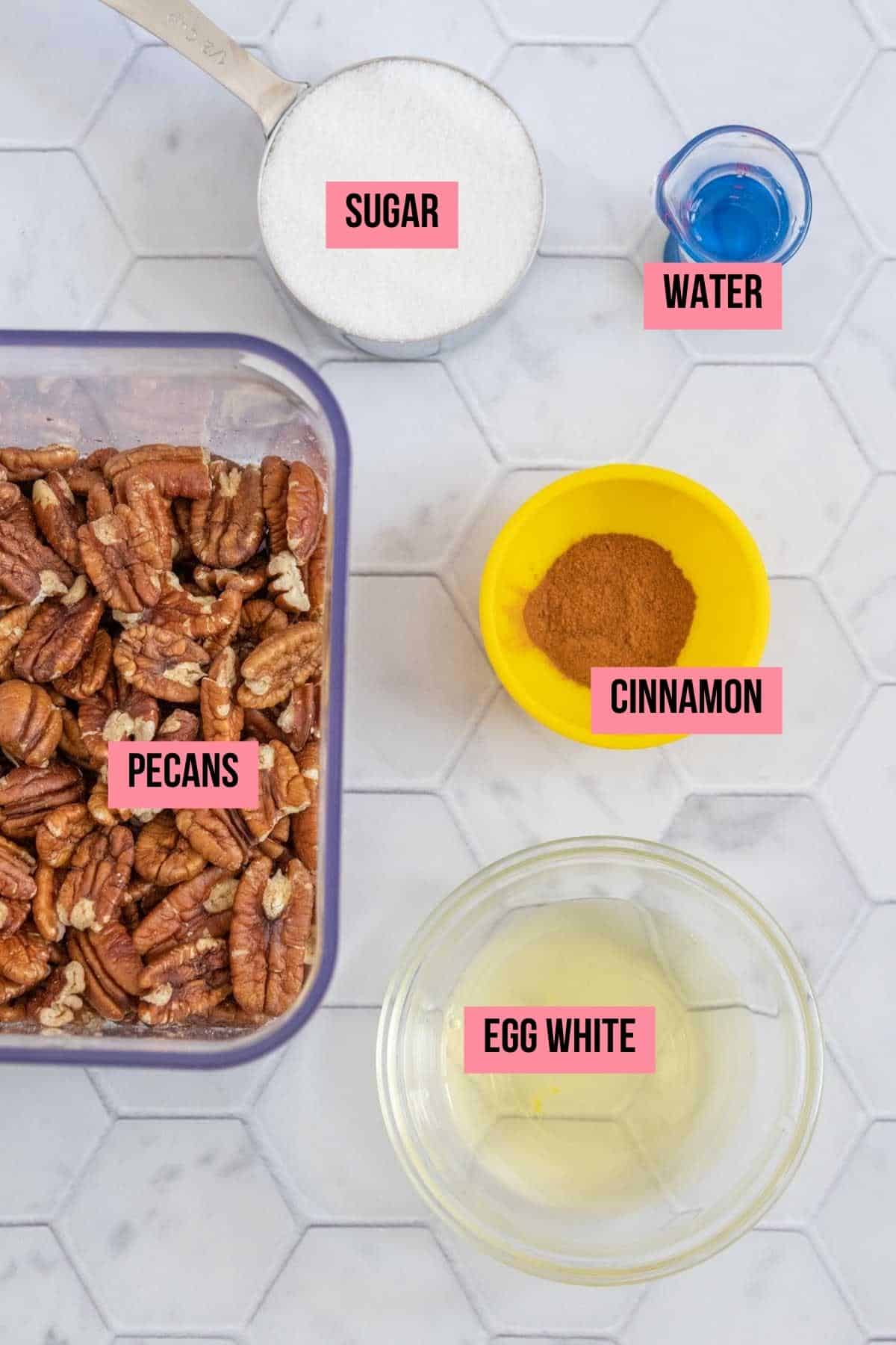 Ingredients for candied pecans on a tile surface with labels.