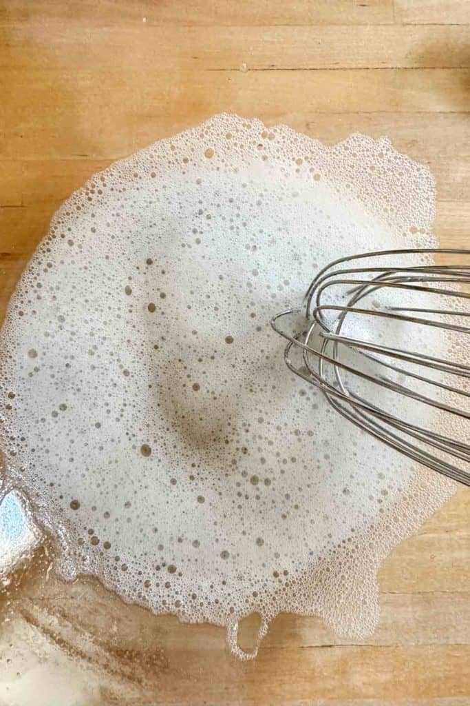 Frothy egg white in a glass mixing bowl.