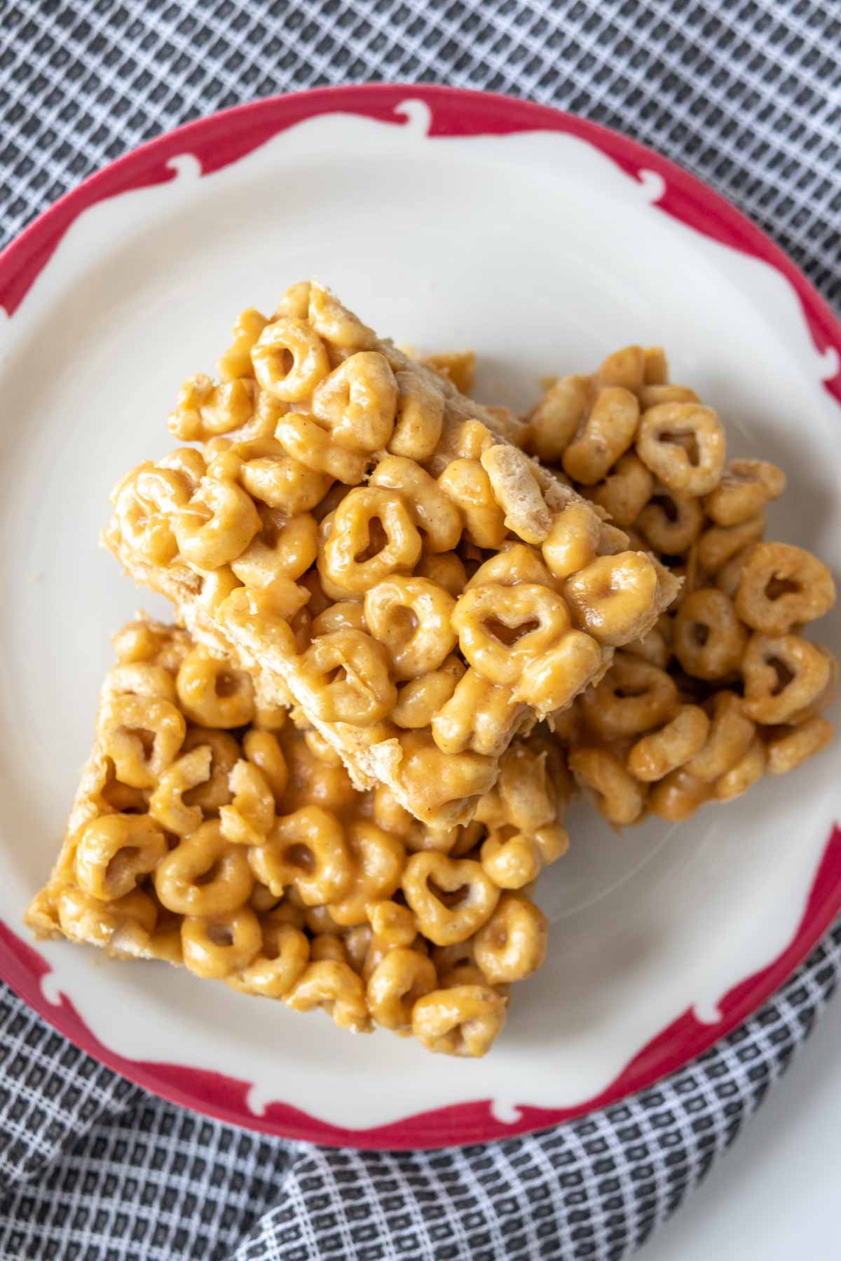 Three sliced cereal bars stacked on a plate with a red edge.