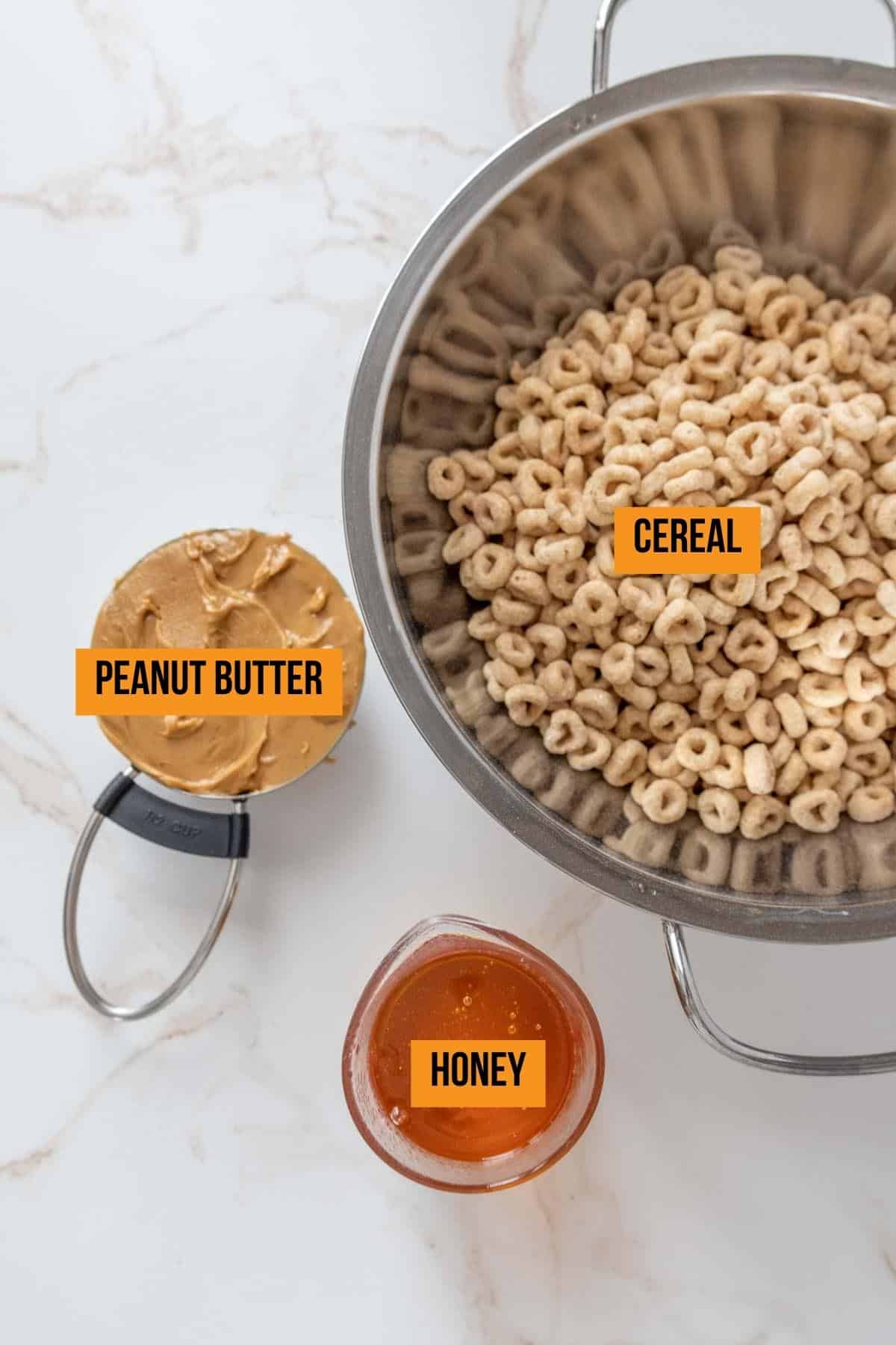 Ingredients for cereal bars on a marble surface with labels.