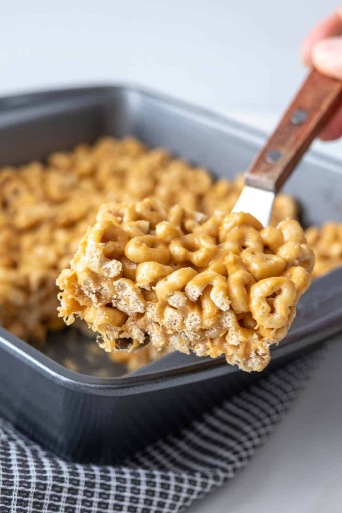 Spatula holding cereal bar up out of pan.
