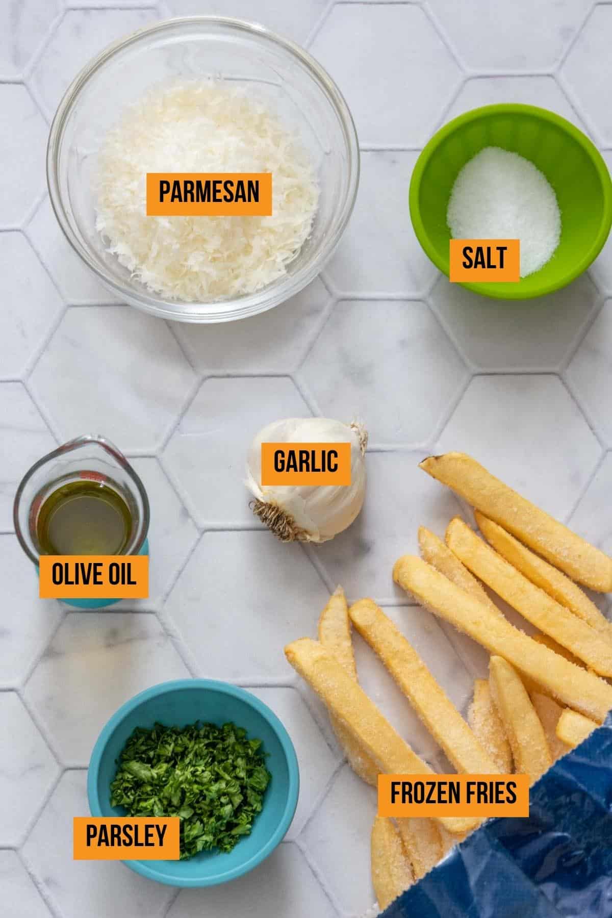 Ingredients for garlic fries on a tile surface with labels.