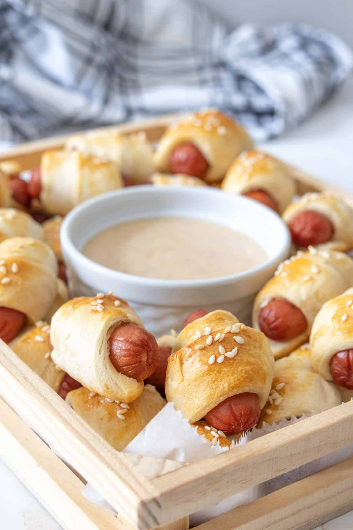 Serving platter of pigs in a blanket with sauce.