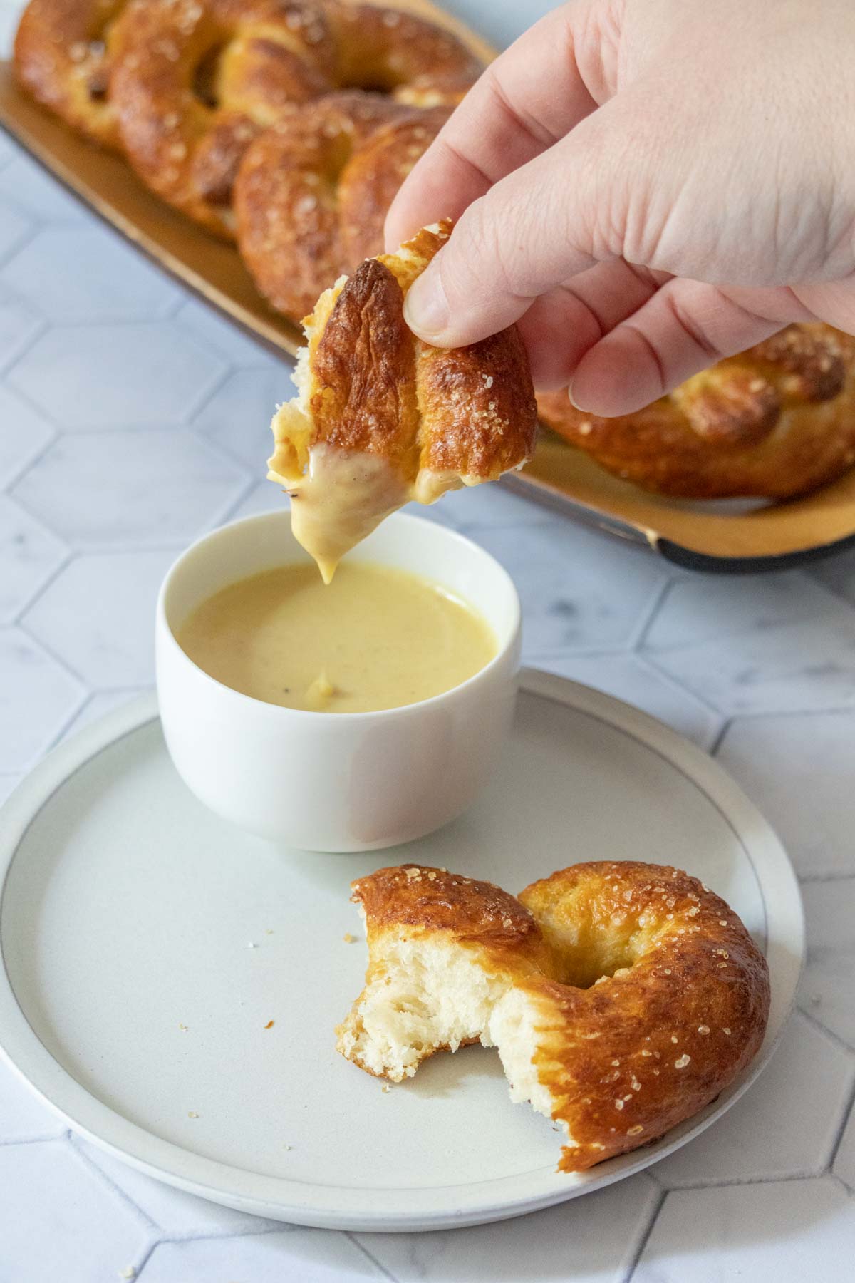 Dipping a piece of homemade soft pretzel into honey mustard sauce.