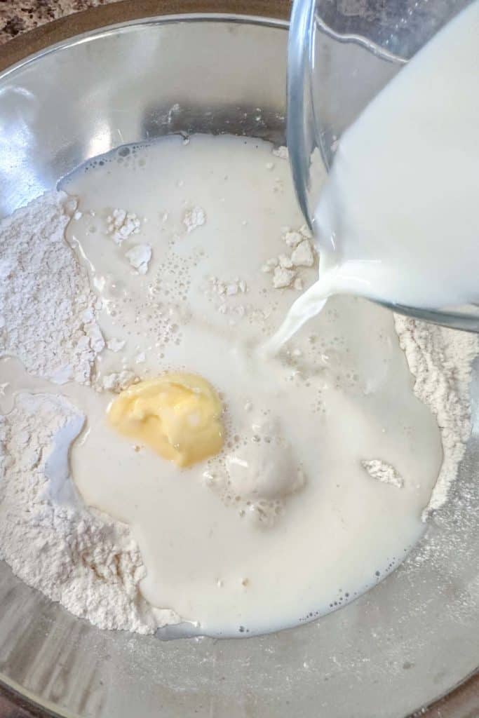 Milk being poured into mixing bowl for dough.