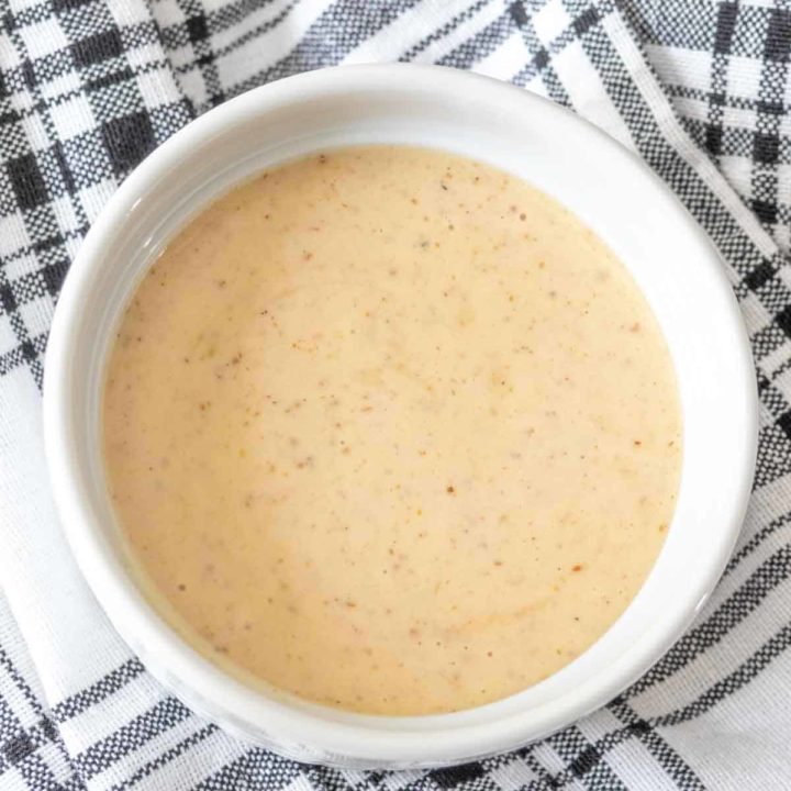 Bowl of dipping sauce in a white bowl on a black and white napkin.