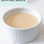 A small white ramekin filled with creamy honey BBQ dipping sauce sits on a white surface, ready to enhance your favorite snacks.