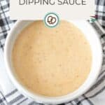 A white bowl filled with light brown dipping sauce sits on a black-and-white checked cloth, with text above reading "Dipping Sauce" to highlight this tasty dipping sauce option.
