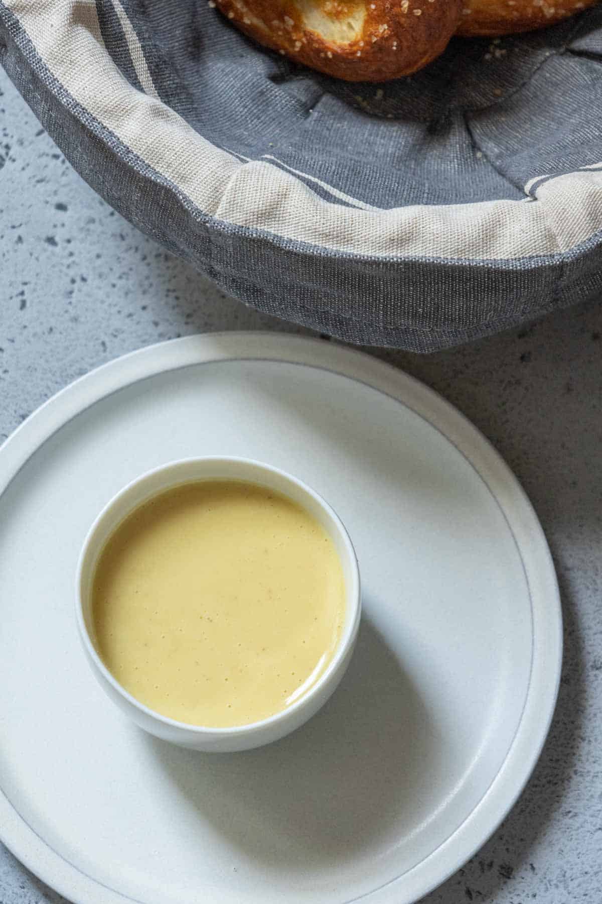 Overhead of small white bowl containing honey mustard sauce on top of a gray plate.
