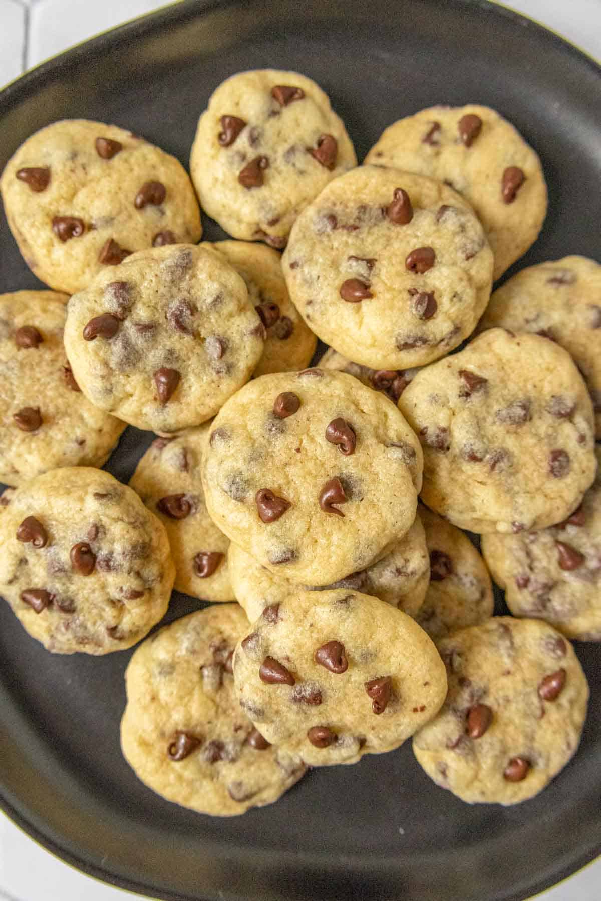 Black plate filled with mini chocolate chip cookies.