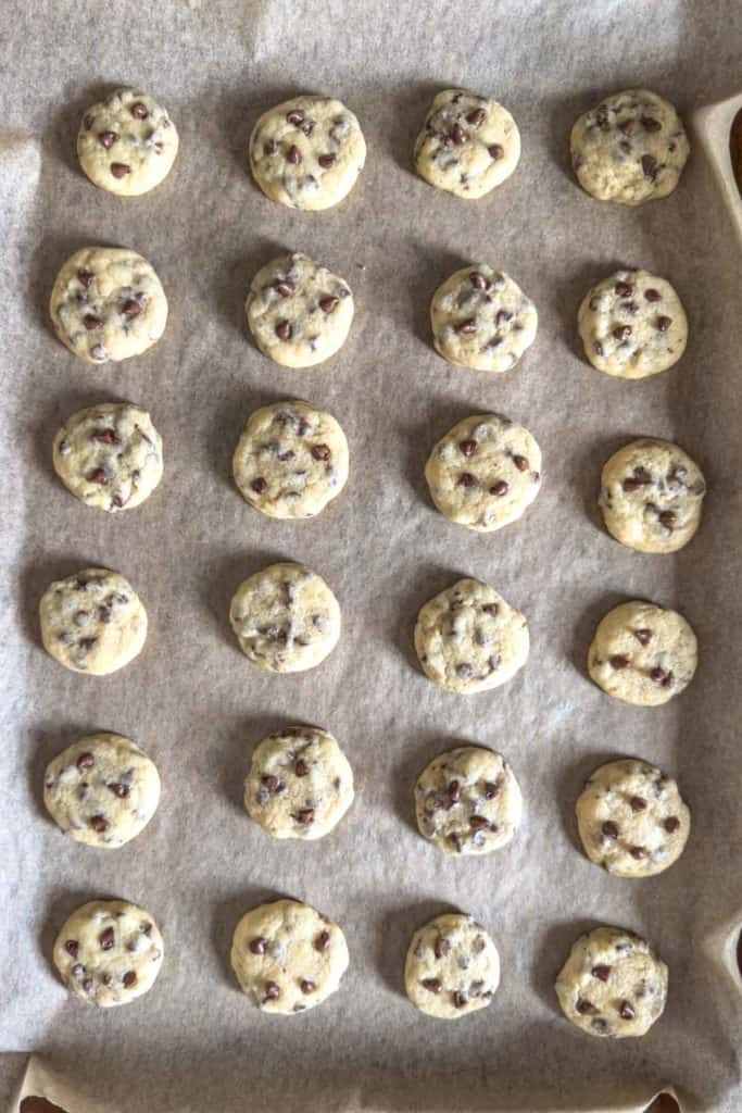Baked mini chocolate chip cookies on baking sheet.