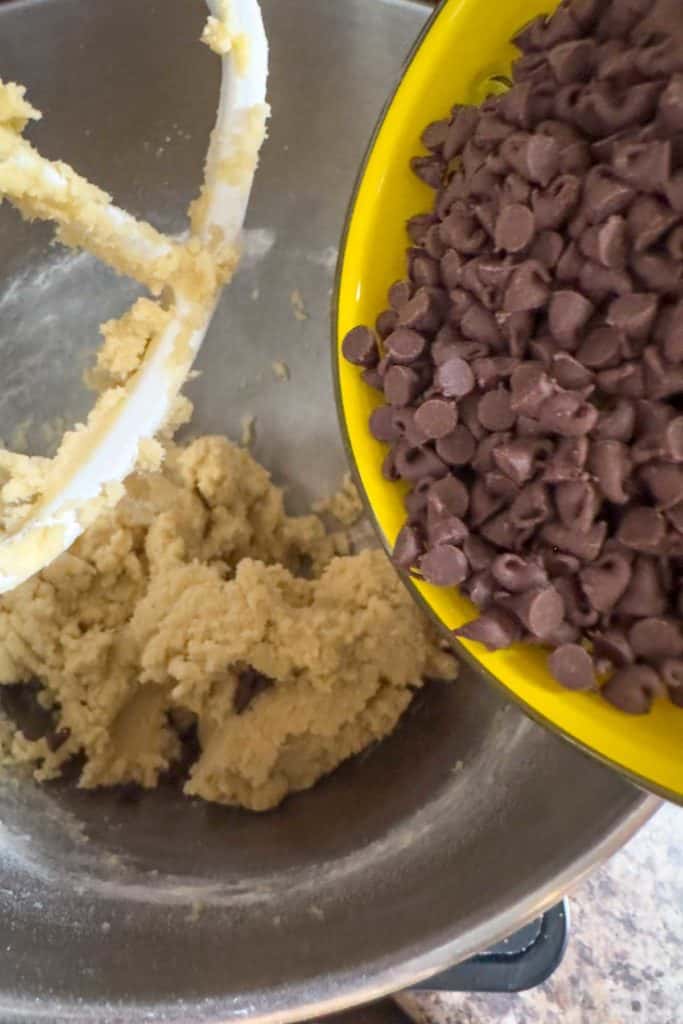 Adding mini chocolate chips to cookie dough.