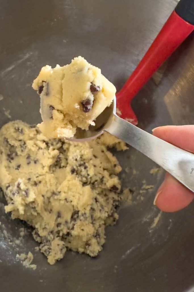 Scooping out 1 teaspoon of cookie dough to make mini cookies.