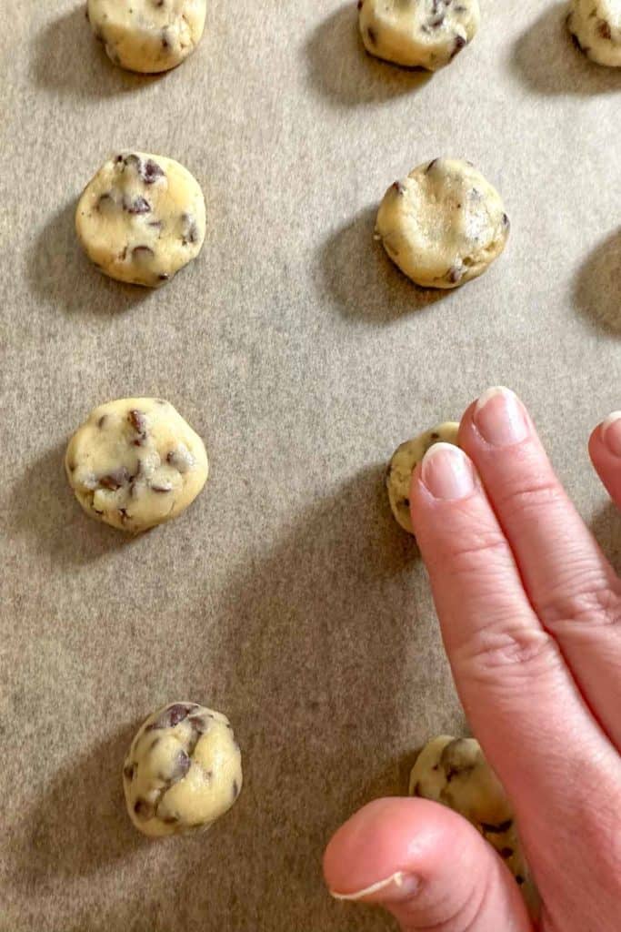 Pressing down cookie dough balls before baking.