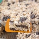 A square of Oreo rice krispie treat is lifted from a pan with an orange spatula. Text at the bottom reads, "Delicious Oreo Rice Krispie Treats.