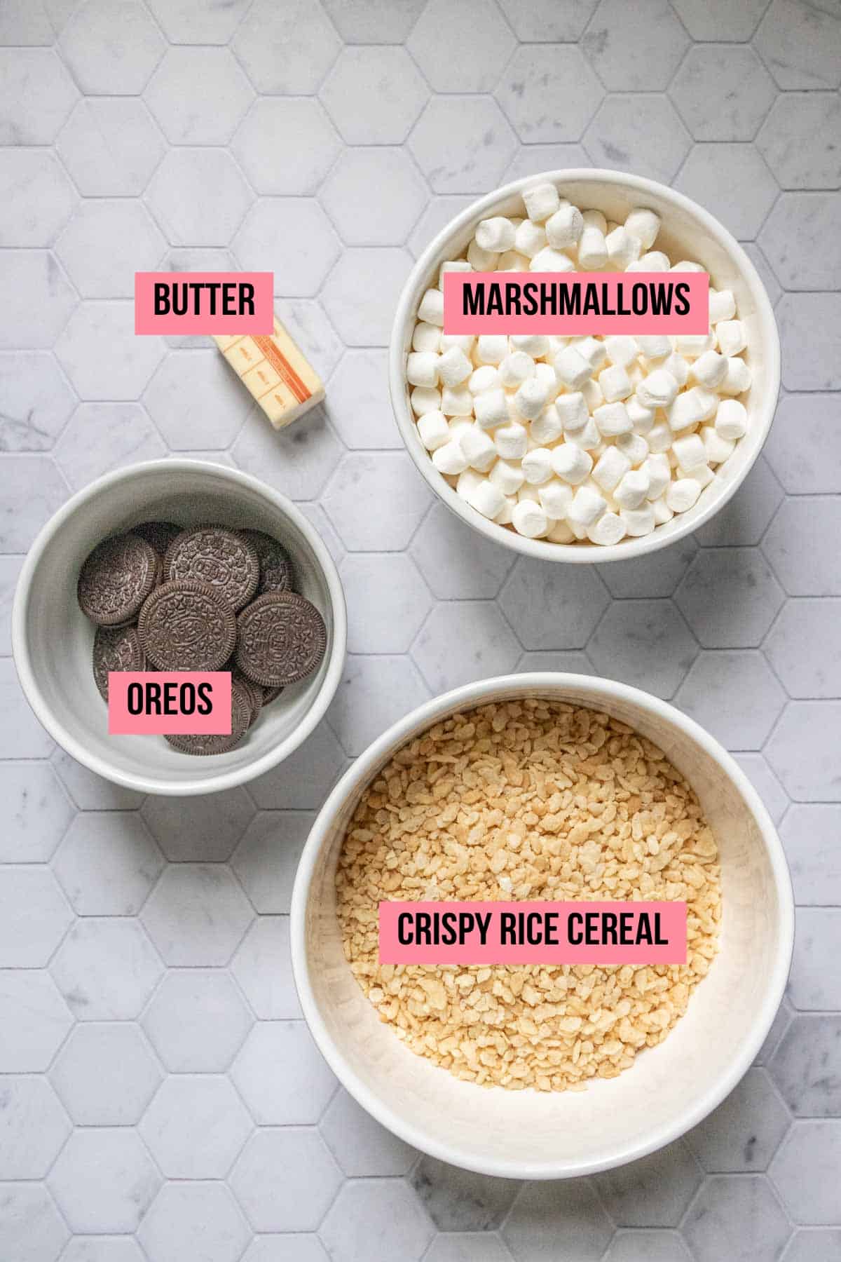 Ingredients for Oreo rice krispie treats on a tile surface with labels.
