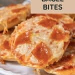 A close-up of pizza bagel bites topped with melted cheese and pepperoni on a white plate. Text overlay reads “Pizza Bagel Bites.”.