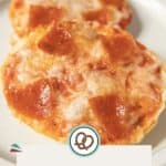 Two pizza bagel bites topped with melted cheese and pepperoni slices, served on a plate. Text overlay reads "Pizza Bagel Bites, happysnackcidents.com.