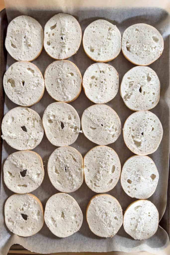 Halved mini bagels on a sheet pan.