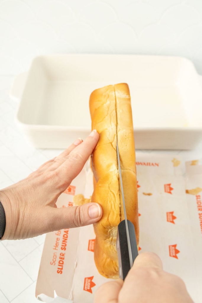 A person cutting a piece of bread with a knife.
