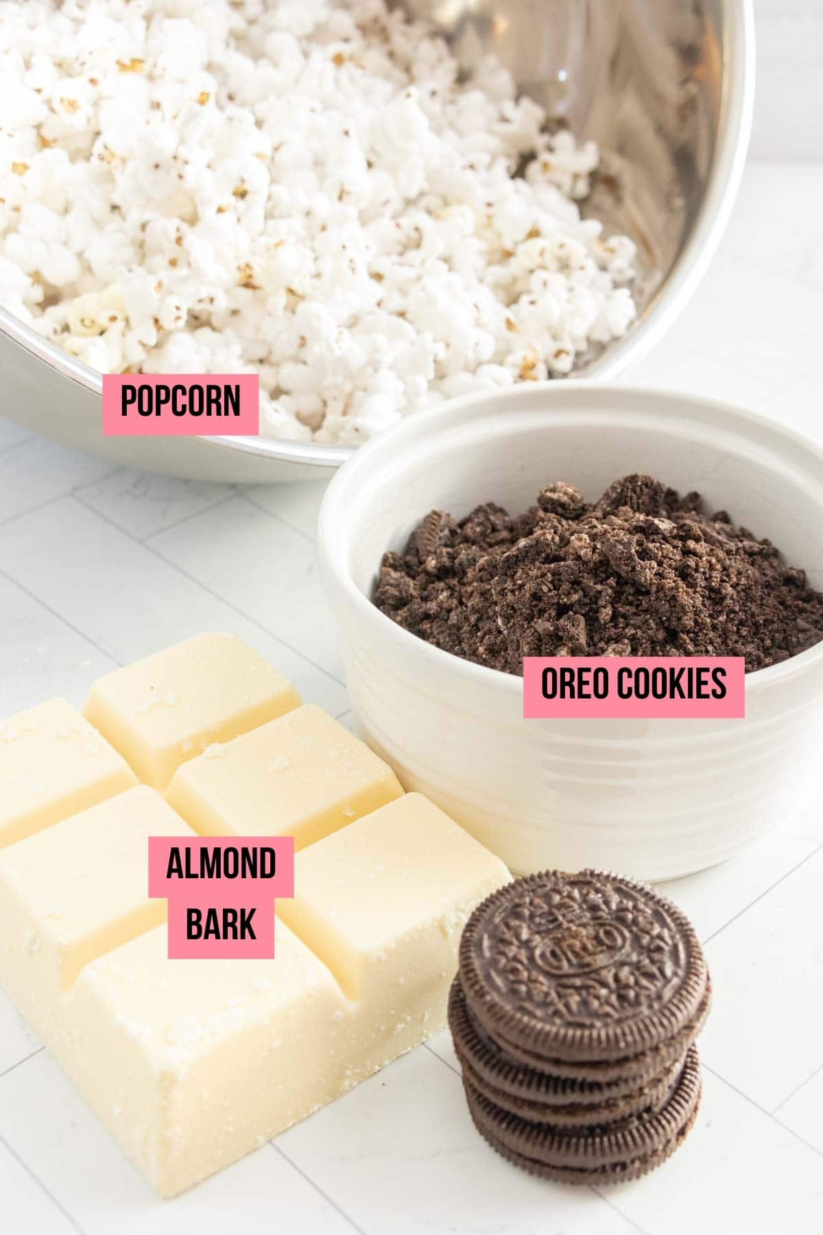 A bowl of popcorn, oreos, almond bark, and chocolate cookie crumbs.