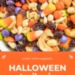 A bowl of Halloween trail mix contains candy corn, raisins, cashews, and colorful chocolate candies. The text reads, "Snack time upgrade! Halloween trail mix" and "HAPPYSNACKCIDENTS.COM".