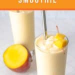 A glass of mango pineapple smoothie with a metal straw and diced mango garnish, an uncut mango, and another smoothie glass in the background. Text reads 'Mango Pineapple Smoothie.' Enjoy the refreshing taste of this delightful blend!