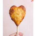 A hand holds a heart-shaped pastry on a stick labeled "Pie Pops" with a website link below.