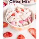 A bowl of strawberry Chex mix with cereal and red and pink candy, surrounded by dried strawberries. Text reads "Strawberry Chex Mix.