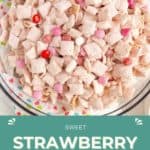 A glass bowl filled with strawberry Chex mix, coated in a pink powder and mixed with pink, red, and white candy pieces.